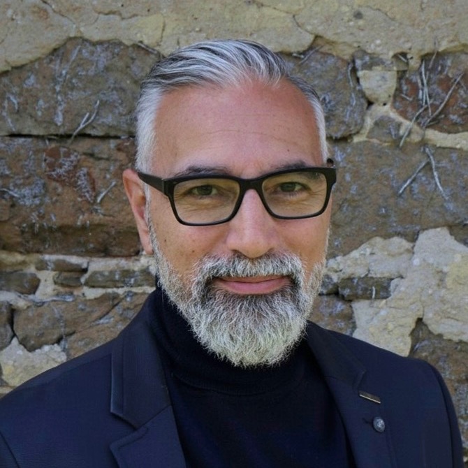 Michael Lauria, headshot in glasses against a stone wall